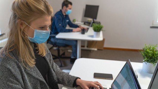 Woman with a facemask at a workstation.